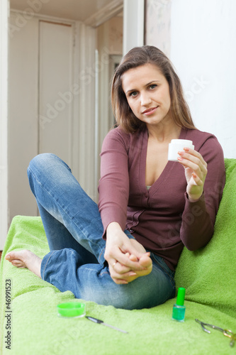Photo: Beautiful woman puts cream on foot Beautiful woman puts cream on foot