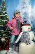 girl with a snowman on the background of a winter landscape