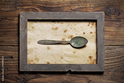 Photo: Metal spoon framed on old wood background Metal spoon framed on old wood background