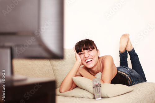 Photo: Attraktive Frau lacht über das Fernsehprogramm Attraktive Frau lacht über das Fernsehprogramm