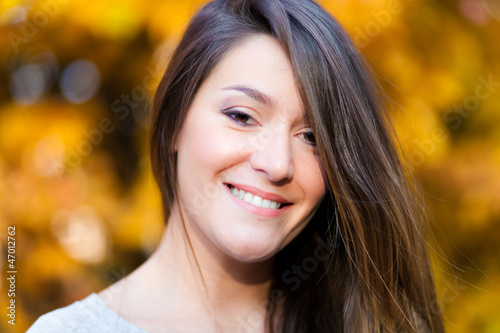Photo: Portrait of beautiful young woman in autumn park Portrait of beautiful young woman in autumn park