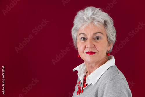 Photo: Ernste ältere Frau in Rot und Grau Ernste ältere Frau in Rot und Grau