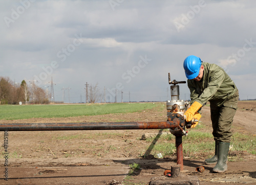 Photo: oil worker closes the valve oil worker closes the valve