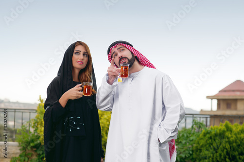 Photo: Arabian couple relaxing in the garden and drinking tea Arabian couple relaxing in the garden and drinking tea