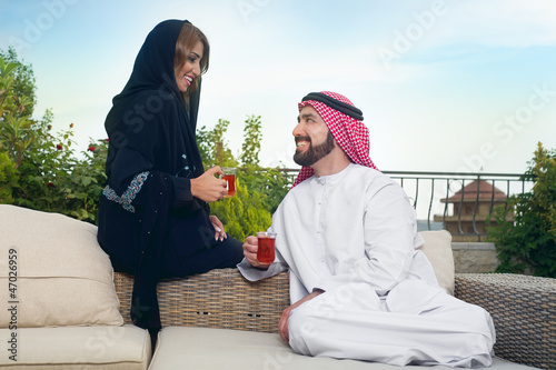 Photo: Arabian couple relaxing in the garden and drinking tea Arabian couple relaxing in the garden and drinking tea