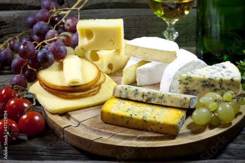 Photo: Cheese and wine various assortment vintage still life in night Cheese and wine various assortment vintage still life in night