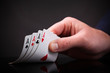 Four aces in the hand on black background