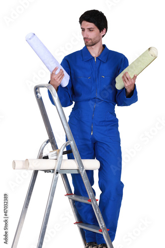 Photo: Man stood on step-ladder choosing which color wallpaper to use Man stood on step-ladder choosing which color wallpaper to use
