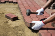 a worker laying red concrete paving blocks.
