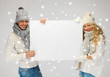couple in a winter clothes holding blank board