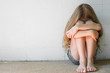sad little girl sitting near the wall