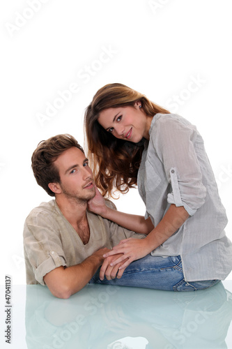 Photo: Young couple sat on glass desk Young couple sat on glass desk