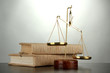 Gold scales of justice and books on grey background