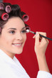 Woman in curlers applying eyeshadow