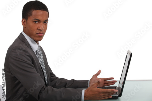 Photo: Disgruntled office worker sat with laptop Disgruntled office worker sat with laptop