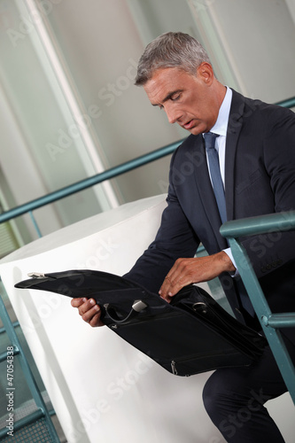 Photo: Businessman rummaging thought his briefcase Businessman rummaging thought his briefcase