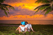 Couple in hug watching together sunset under palm tree