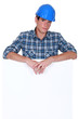 Downbeat manual worker stood with blank poster