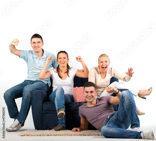 Photo: Young people sitting on a sofa and cheering, on white background Young people sitting on a sofa and cheering, on white background