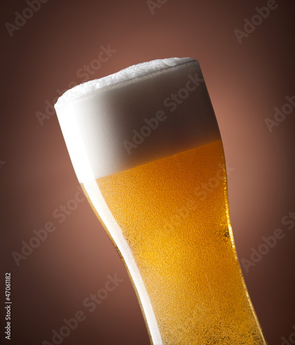 Photo: full glass of beer on a brown full glass of beer on a brown