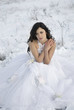 pretty young woman posing in wedding dress  on winter snow