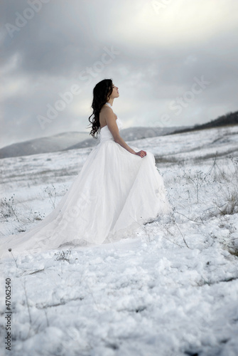 Photo: pretty young woman posing in wedding dress on winter snow pretty young woman posing in wedding dress on winter snow