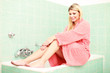 Attraktive junge Frau auf der Kante einer Badewanne sitzend