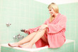 Hübsche Frau im Bademantel auf der Badewanne
