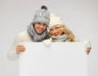couple in a winter clothes holding blank board