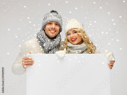 Photo: couple in a winter clothes holding blank board couple in a winter clothes holding blank board