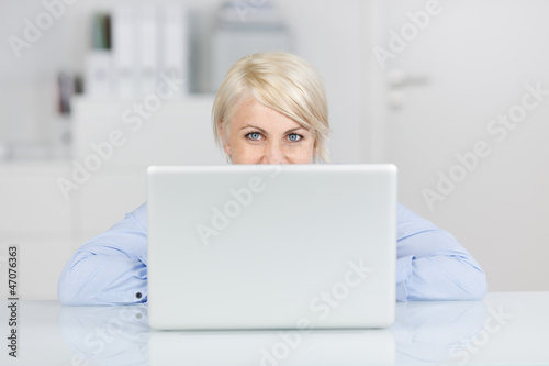 Photo: frau im büro schaut über laptop frau im büro schaut über laptop