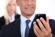Man using a cellphone with his assistant in the background