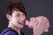 Gepiercter junger Mann mit Sparschwein