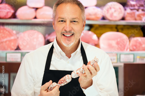 Photo: Man showing a salami in a grocery store Man showing a salami in a grocery store