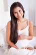 Smiling pregnant woman in bed