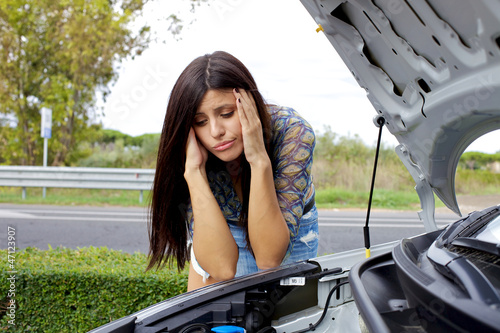 Photo: Desperate woman looking at broken engine of her car Desperate woman looking at broken engine of her car
