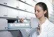 Photo: Young female pharmacist reaching for medicine Young female pharmacist reaching for medicine