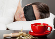 Man with Sleeping mask sleep on a bed, cup of herbal tea in the