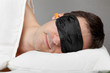 Man with Sleeping mask sleep and earplugs lying in bed