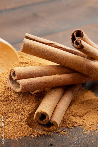 Photo: Cinnamon sticks and cinnamon powder in wooden scoop Cinnamon sticks and cinnamon powder in wooden scoop