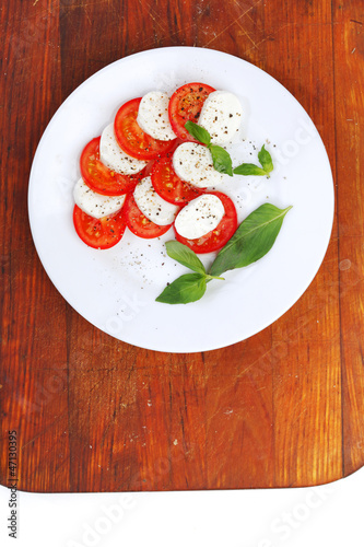 Photo: Mozzarella cheese tomato and basil on a plate Mozzarella cheese tomato and basil on a plate