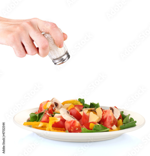 Photo: Hand adding salt using salt shaker isolated on white Hand adding salt using salt shaker isolated on white
