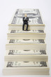 Photo: Businessman figurine sitting on stack of dollars Businessman figurine sitting on stack of dollars
