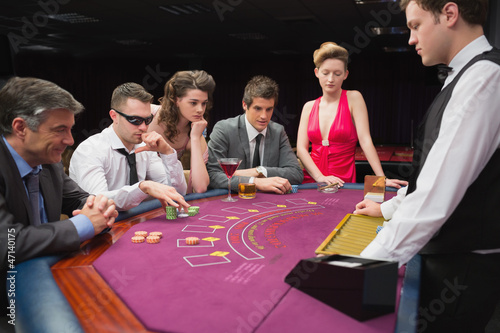 Photo: People sitting at table playing poker People sitting at table playing poker