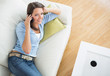 Brunette woman lying on sofa and calling