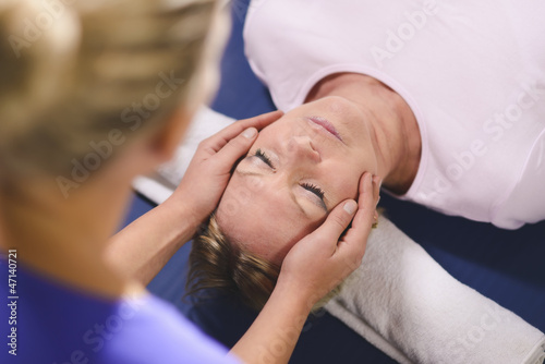 Photo: Young therapist doing reiki therapy to senior woman Young therapist doing reiki therapy to senior woman