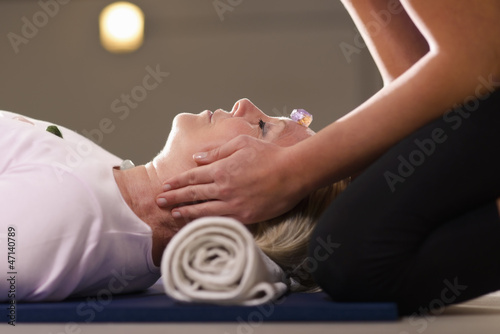 Photo: Young therapist arranging crystals on female client for reiki th Young therapist arranging crystals on female client for reiki th
