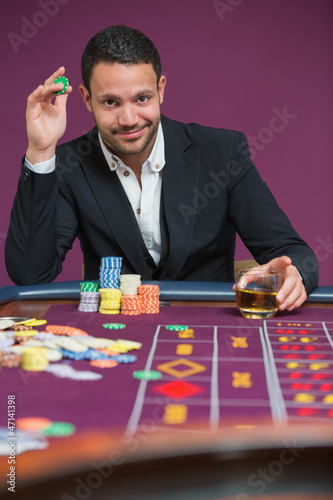Photo: Man holding a chip and a glass of whiskey Man holding a chip and a glass of whiskey