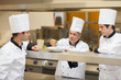 Head chef showing others how to garnish plate