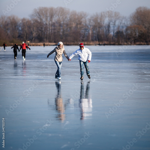 Photo: Couple ice skating outdoors on a pond Couple ice skating outdoors on a pond